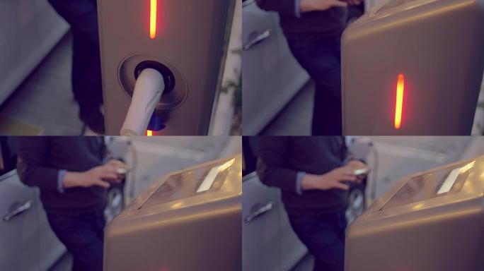 男子在为电动汽车充电时使用智能手机