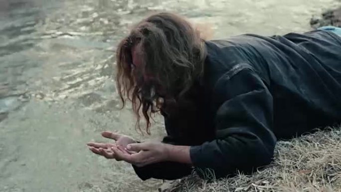 一个无家可归的乞丐躺在河边，洗手洗脸