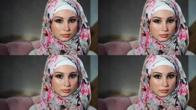 年轻的穆斯林妇女，戴着头巾的眼睛，看着相机，慢慢地眨眼