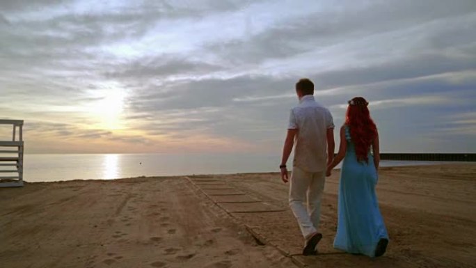 日出时在海边散步的情侣。情侣海滩