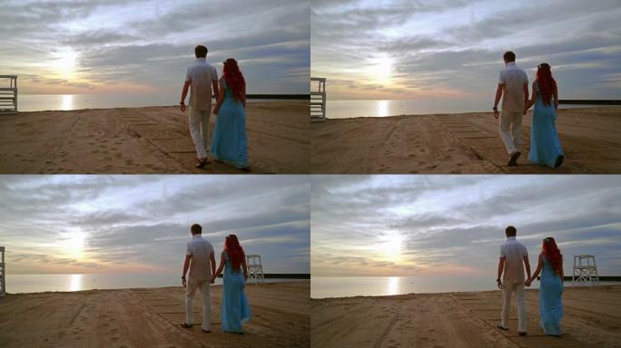 日出时在海边散步的情侣。情侣海滩