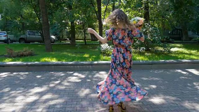 美丽的年轻女子正拿着一束鲜花在公园里跳舞。