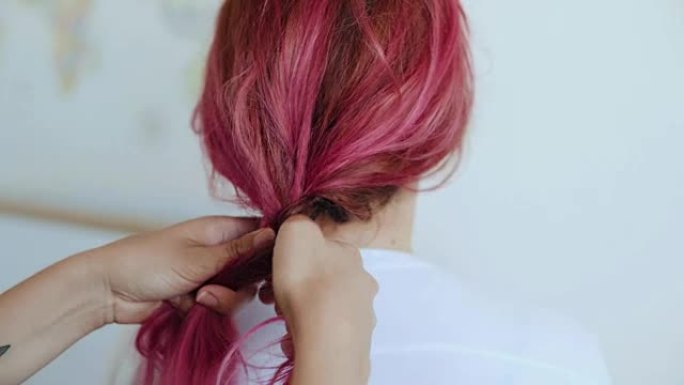 朋友给粉红色头发的女孩做辫子