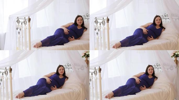 床上穿着蓝色连衣裙的孕妇