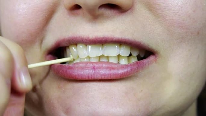 用牙签从牙齿上采摘食物