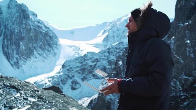 无人机遥控。无人机飞行员操作员的手和远程视图。雪山中的旅行者拍照并检查了领土。