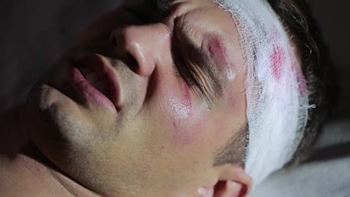 头部受伤的人躺在床上。包扎的头。他脸上有瘀伤。