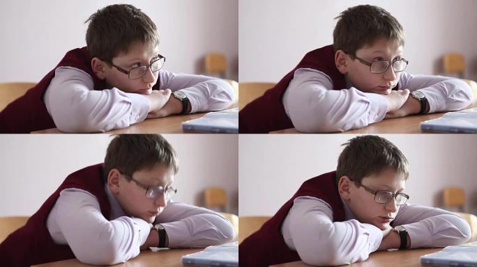 戴眼镜的悲伤男孩坐在教室里