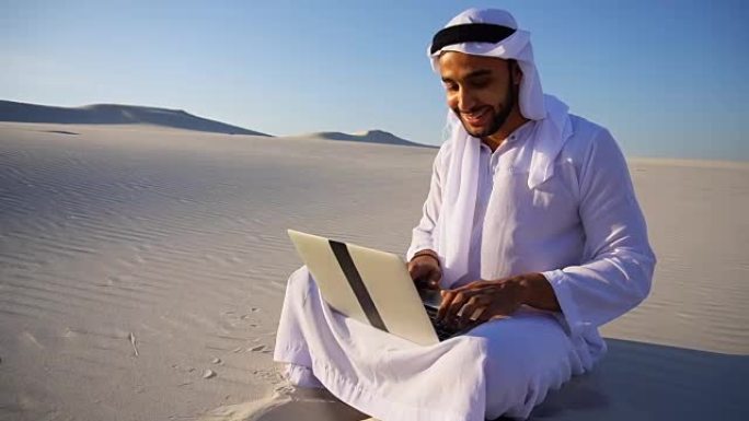 阿联酋谢赫的专业电脑项目设计师，在夏夜坐在沙漠的沙子上