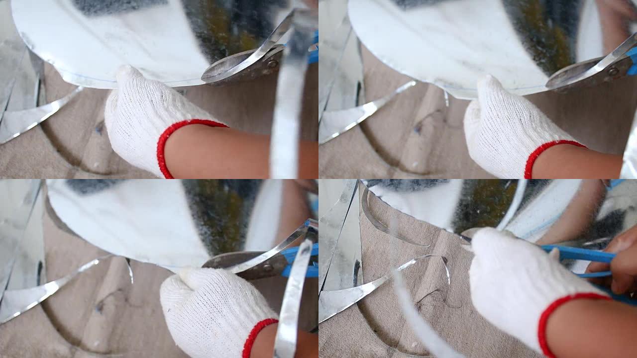 技术人员的手使用硬剪刀切割一片铝锌，用于圆形布局形状