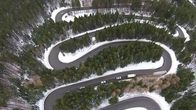 卡车和汽车缓慢地穿越危险的弯道和高山路的转弯，在冬季条件下，鸟瞰图