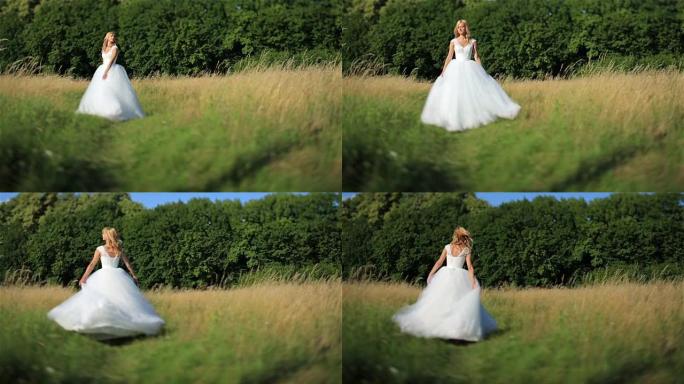 美丽浪漫时尚的金发新娘穿着白色连衣裙在阳光下的绿色田野中跳舞