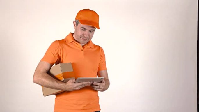穿着橙色制服的送货员使用他的平板电脑给顾客一个包裹。灰色背景全高清孤立镜头