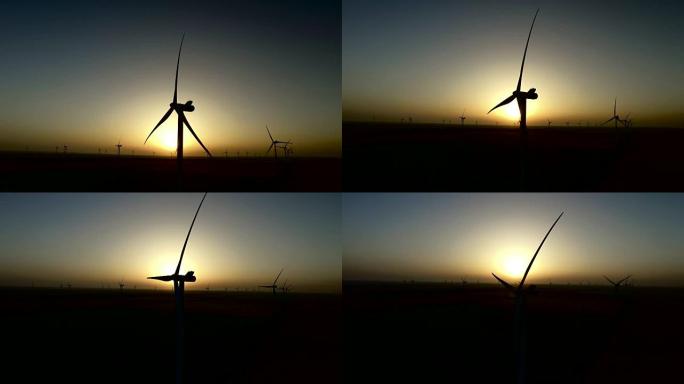 在彩色的夏季日落时，麦田里的风力涡轮机工作。轮廓。航空摄影测量