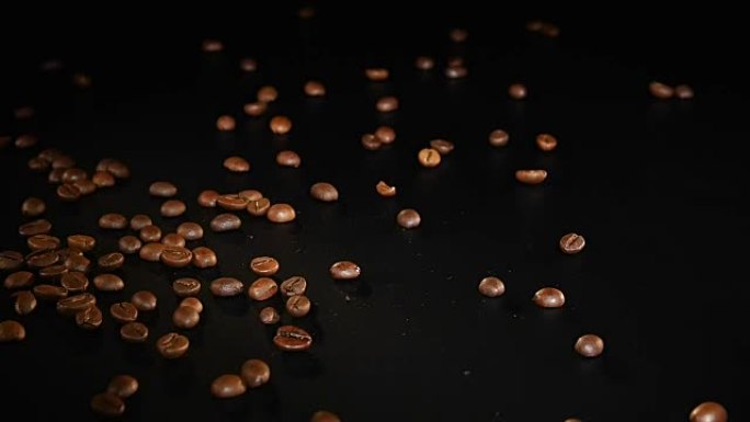 咖啡豆-掉落。以96 FpS的速度拍摄咖啡豆落在黑色表面上。任何咖啡相关主题或标题背景的漂亮通用镜头