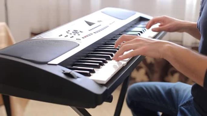 男性手弹钢琴的特写镜头。玩合成器键盘的人。