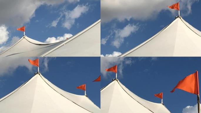橙色三角旗在白色帐篷上随风飘扬