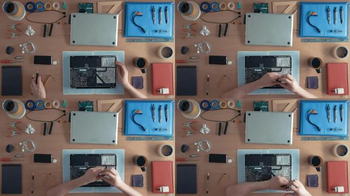 俯视图技术员工程师正在修理桌子上的笔记本电脑，周围是用品和设备