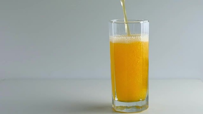 用吸管将橙色汽水倒入玻璃杯中