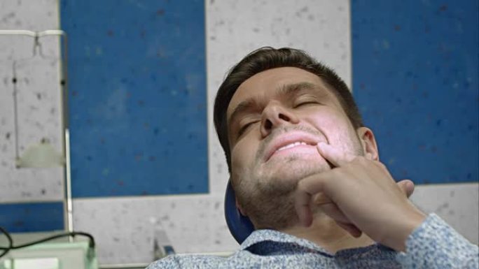 牙科诊所的男性客户向牙医展示了痛处