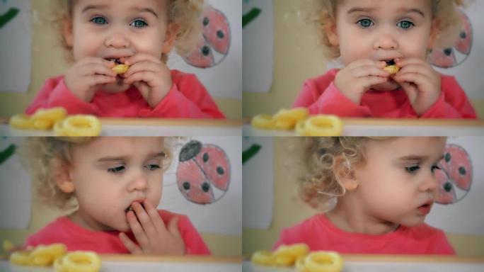 小女孩吃玉米圈坐在桌子旁边，玩具和墙上的图画