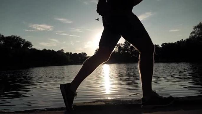 超级慢动作steadicam剪辑的男性跑步者日落剪影靠水