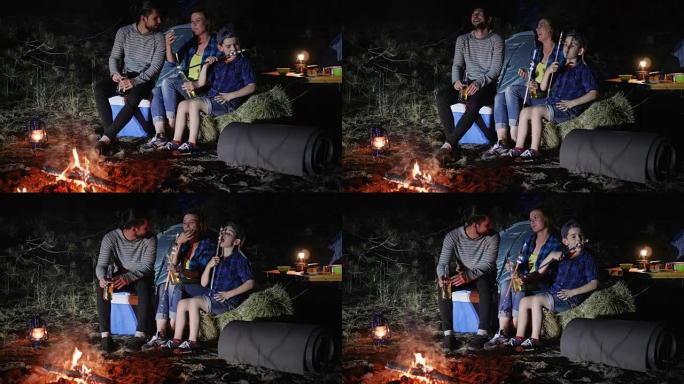 美国家庭在林地的旅行营地，父母喝啤酒，孩子带着帐篷在篝火旁吃zephyr