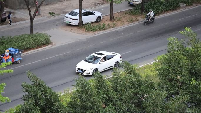 行驶在马路上的白色日产轩逸小轿车