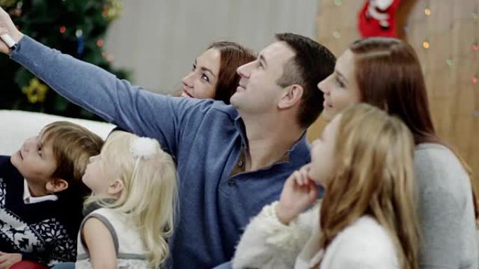 快乐的家庭在圣诞晚会上用自拍杆拍照