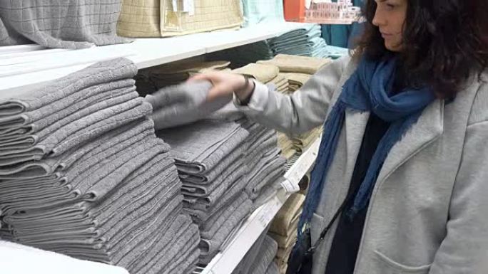 在百货商店选择灰色毛巾布的女人