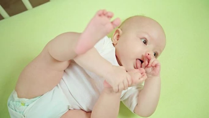婴儿躺在家里的婴儿床里吃脚趾
