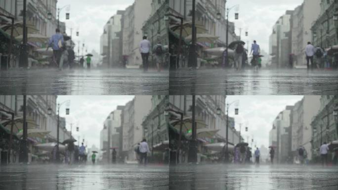 城市街道大雨日的背景。实时。雨中带伞的人上下班。模糊的波克。自然背景