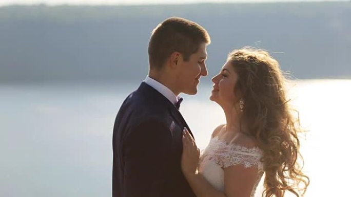 迷人的微笑的妻子和她的丈夫在他们一生中最美好的一天接吻。婚礼当天。