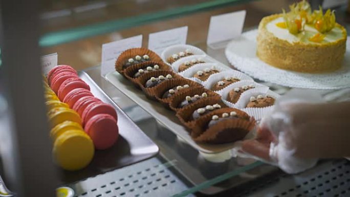 咖啡和糕点吧。计数器。甜点暴露在玻璃表面上。右边是多色的法式马卡龙。左边是美味的水果蛋糕。咖啡馆的员