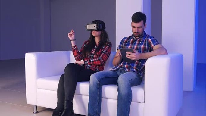 高科技夫妇: 女孩使用虚拟现实设备，而年轻人在他的数字平板电脑上打字