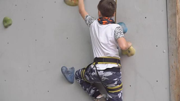 小男孩在室内攀岩健身房的墙壁上锻炼