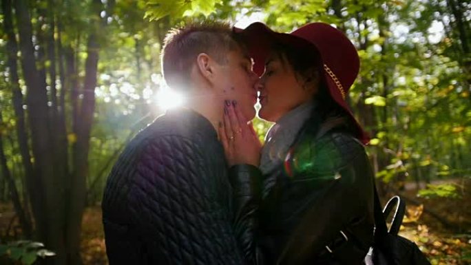 恋爱中的情侣在日落时在秋天的公园里接吻，慢动作
