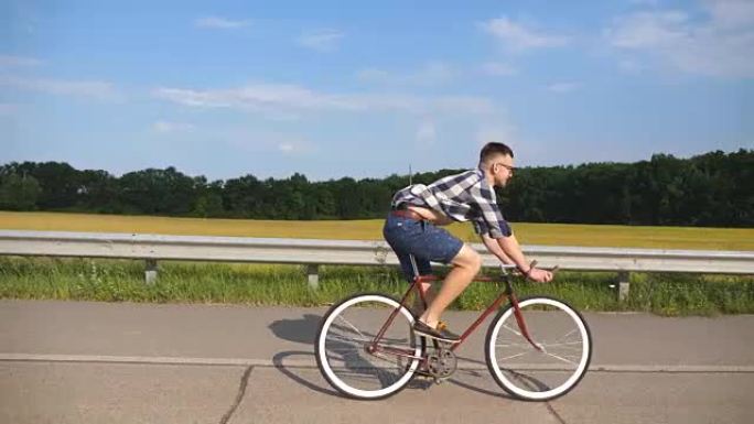 年轻英俊的男人骑着乡村公路上的老式自行车。运动的家伙在赛道上骑自行车。男性骑自行车的人在高速公路上骑