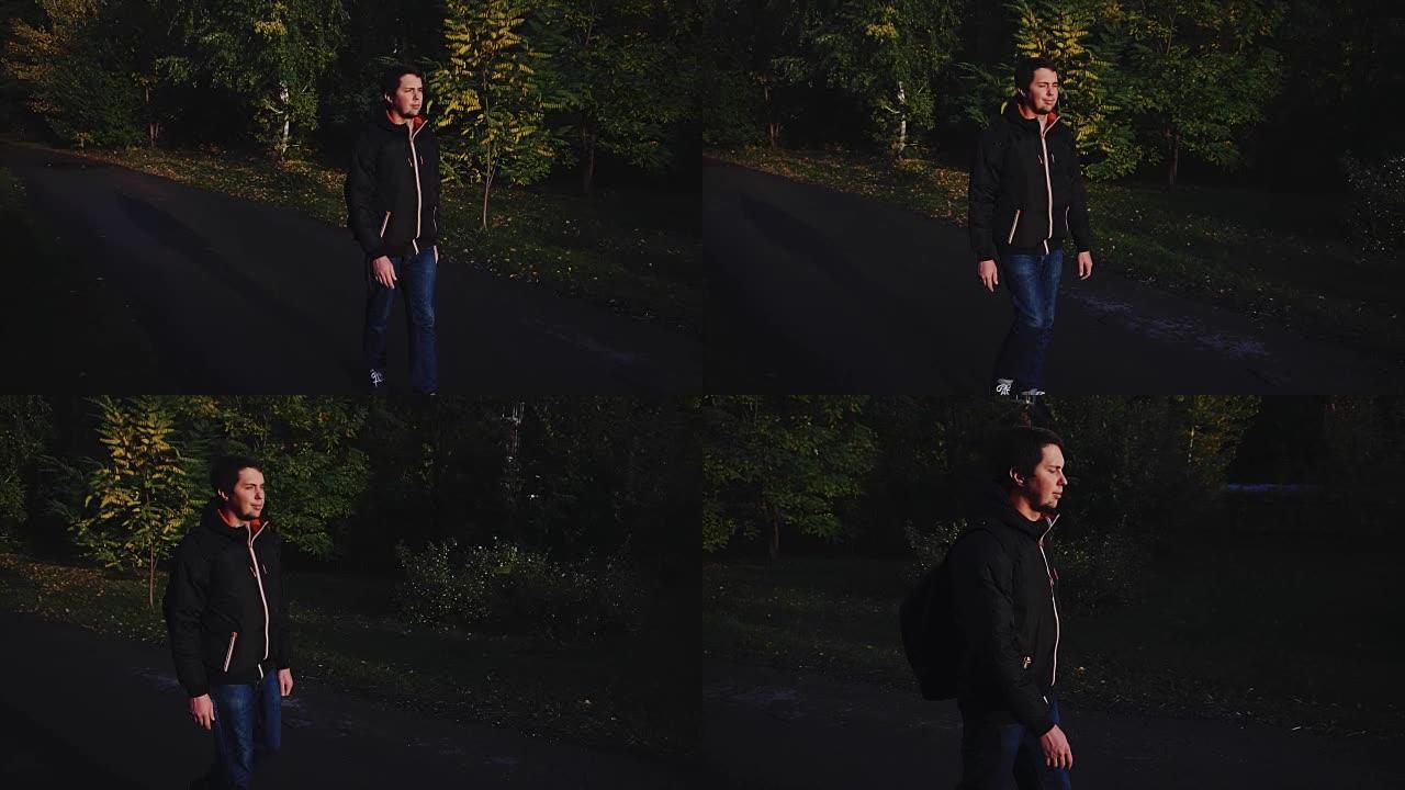 穿着黑色夹克的年轻冷静的人走在秋天的公园戏剧性的光