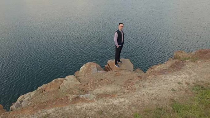 人站在湖边的悬崖边。