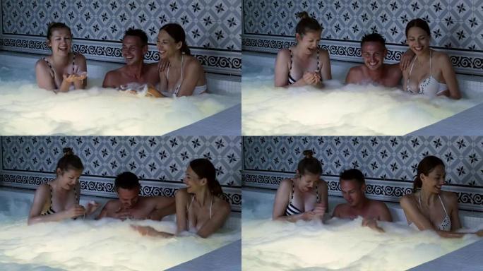 快乐的两个女孩和男人放松享受热水浴缸
