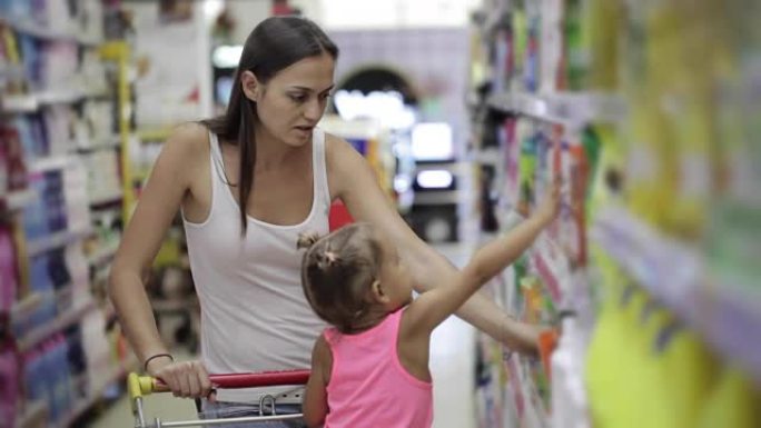 有小女儿的年轻妇女在超市为家里选择洗涤剂