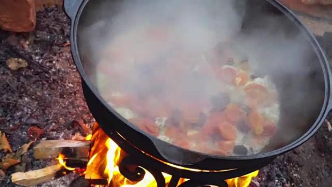 用铸铁大锅在火上煮肉。