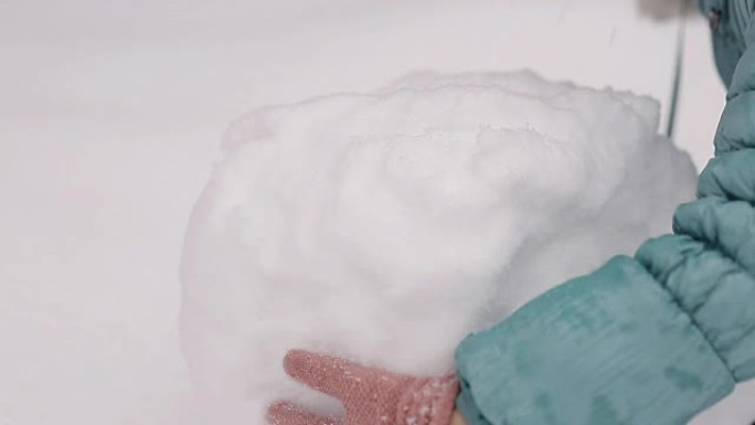 女孩在冬天的雪地里雕刻雪人。