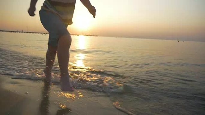 赤脚小孩在日落时在海水中奔跑
