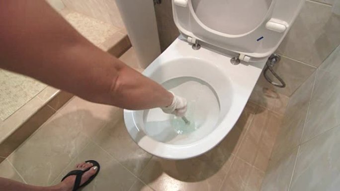 女人戴着手套在家里或酒店房间的浴室清洁马桶