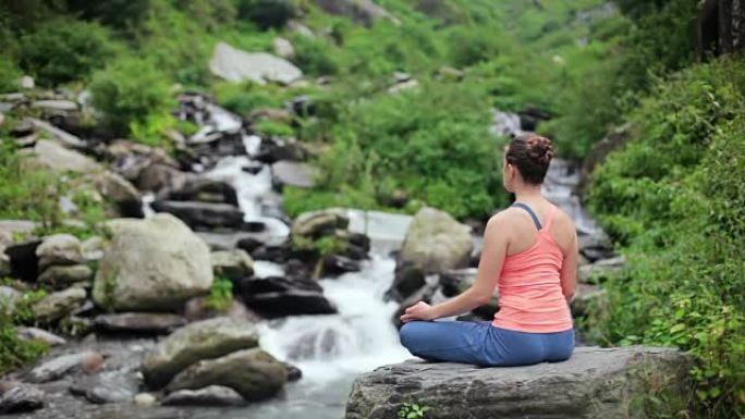 女人在莲花的热带瀑布上冥想姿势Padmasana