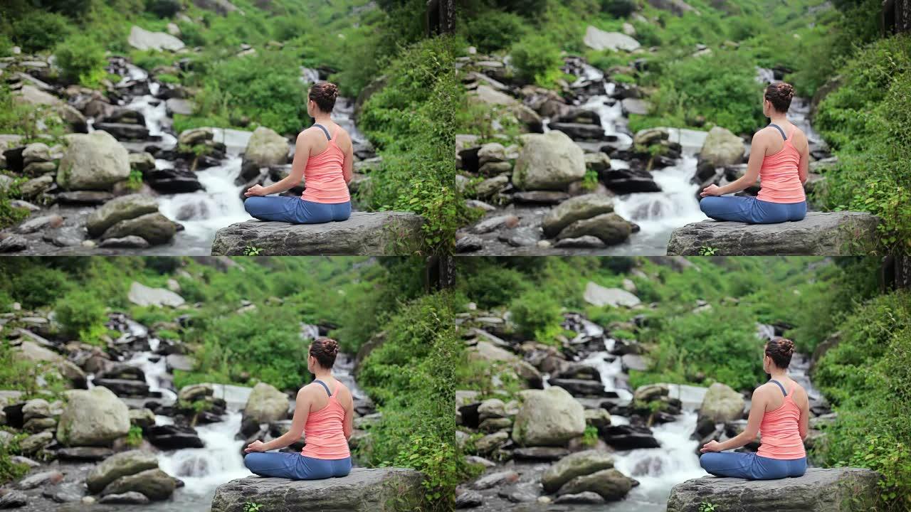 女人在莲花的热带瀑布上冥想姿势Padmasana
