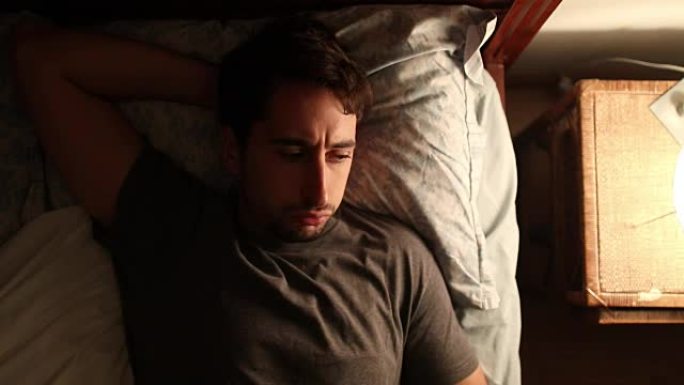 男人在半夜醒来-打开床头柜的灯担心失眠并起床。面容体贴的人关心某事