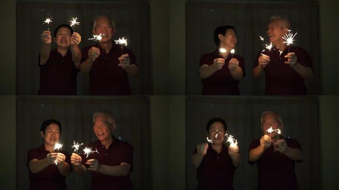 亚洲老夫妇玩烟花，烟花，爆竹在晚上。庆祝生活的概念